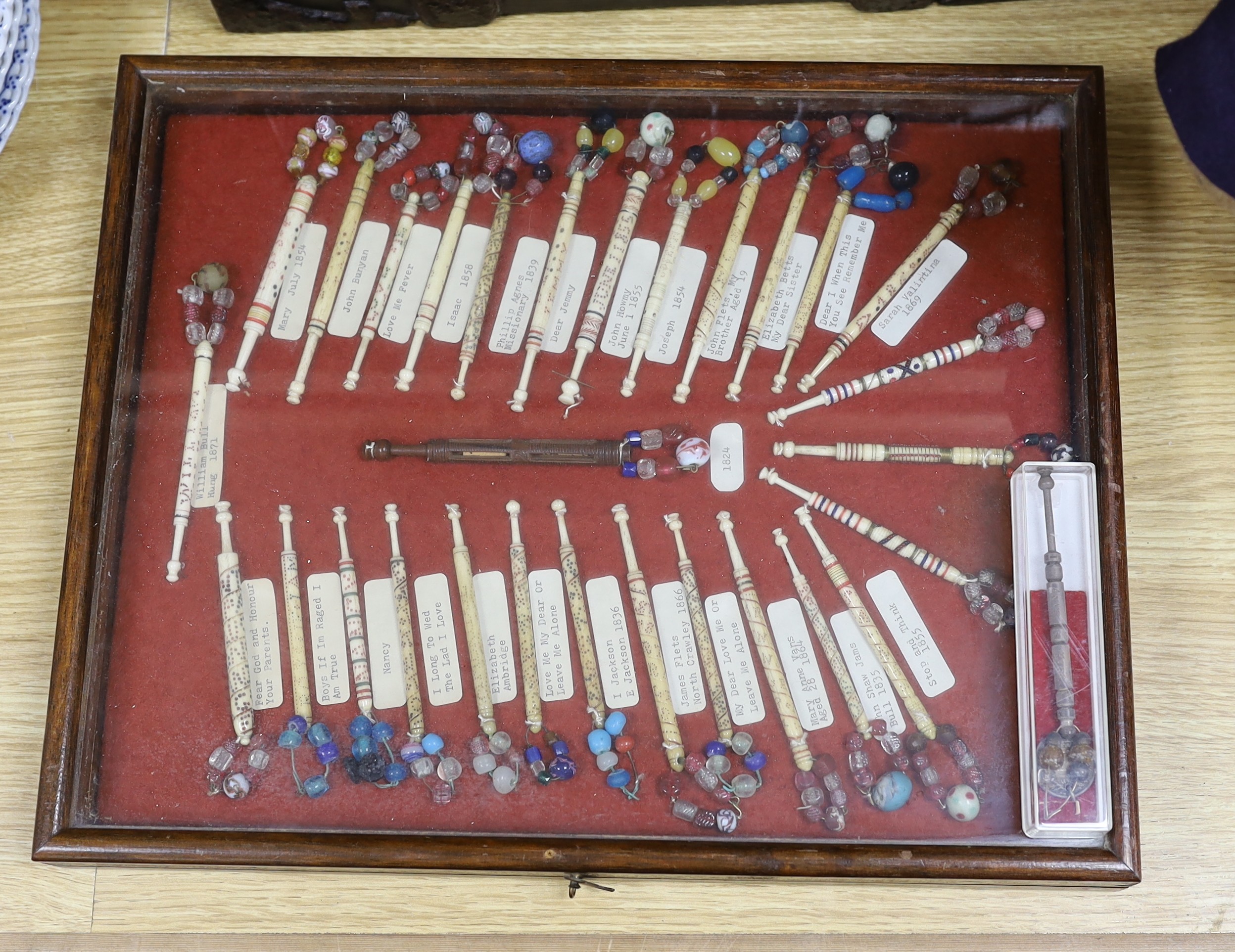 A cased collection of 19th century inscribed bone and glass bead lace bobbins, some dated and named